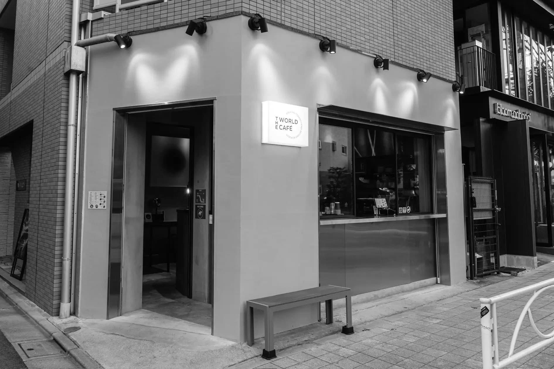 The World Cafe, a corner cafe in Nakameguro, Tokyo, with its counter window open to the street at dusk.